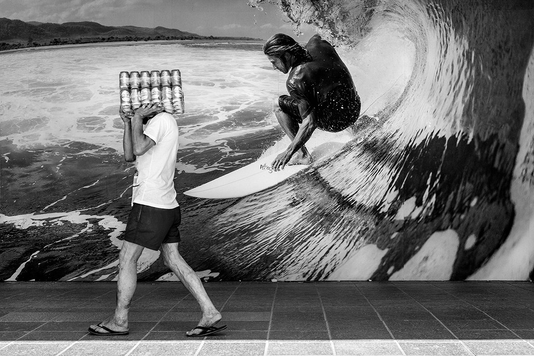 A person walks in front of a picture of a surfer riding a wave.